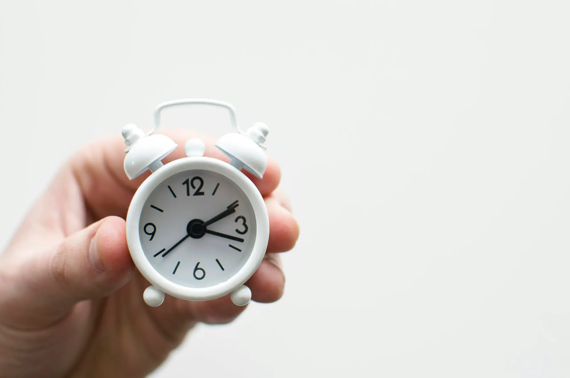A hand holding a small alarm clock, a reminder of the deadline a short-term loan has to meet