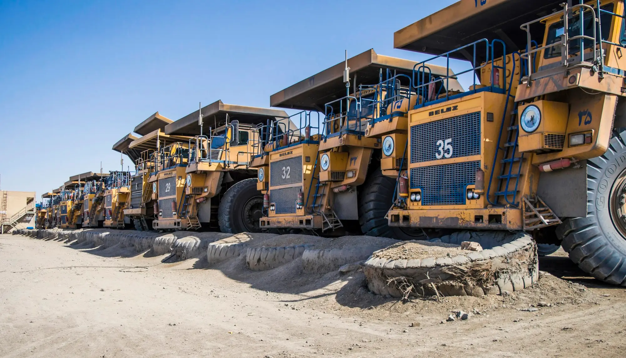 A row of large yellow trucks parked in a yard, a fleet funded with a bigger business loan
